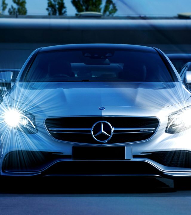 Front view of a lineup of Mercedes-Benz cars with bright headlights, showcasing luxury and elegance.